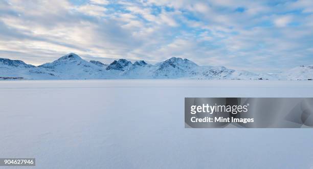 winter landscape under a cloudy sky, with mountains in the distance. - greenland stockfoto's en -beelden
