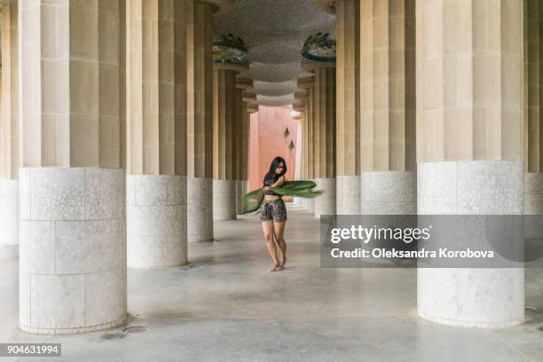 fashionable young woman with a green scarf between the columns in park gruell in barcelona, spain. - park guell stock pictures, royalty-free photos & images