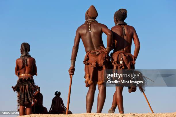 small group of himba men wearing traditional clothing standing in a desert. - himba photos et images de collection