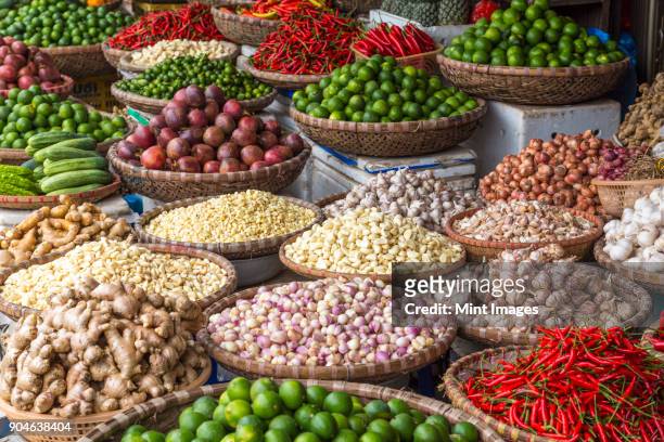high angle close up of baskets vegetables and spices at a market, including chilies, limes, garlic, ginger. - vietnamese mint stock pictures, royalty-free photos & images