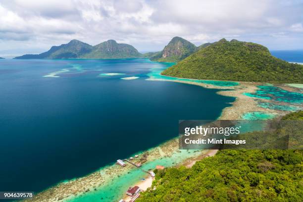 high angle view along coastline of tropical island, mountains in the distance. - île de bornéo photos et images de collection