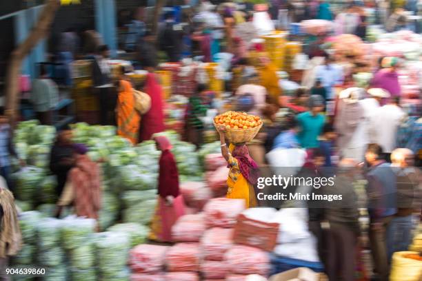 high angle view of fruit and vegetable market, woman carrying a load on her head, motion blur. - india market stock pictures, royalty-free photos & images