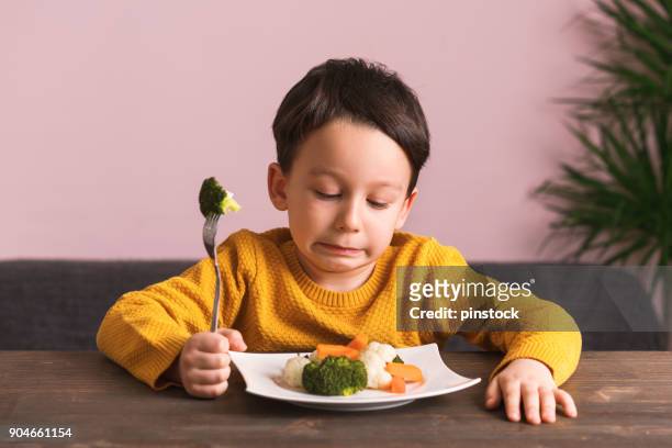 niño está muy contento con tener que comer verduras. - disgust fotografías e imágenes de stock