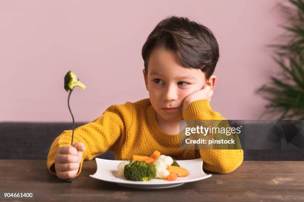 niño está muy contento con tener que comer verduras. - quejándose fotografías e imágenes de stock