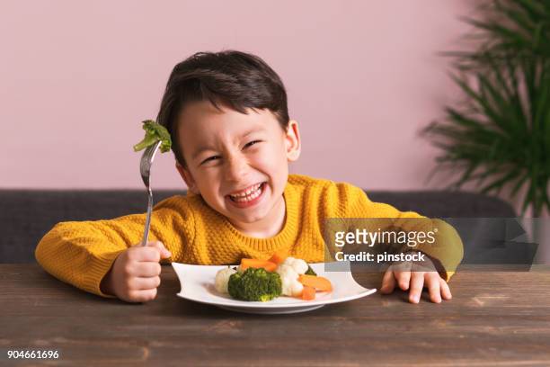 child is eating vegetables. - healthy eating children stock pictures, royalty-free photos & images