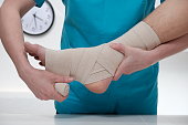 Close-up of male doctor bandaging foot of female patient