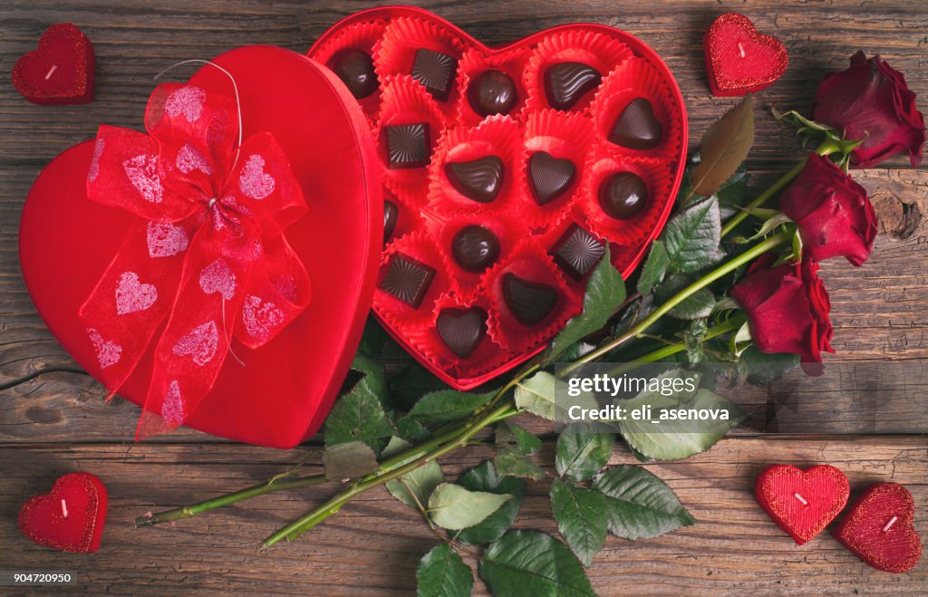 Heart chocolate box and red roses on wooden rustic background