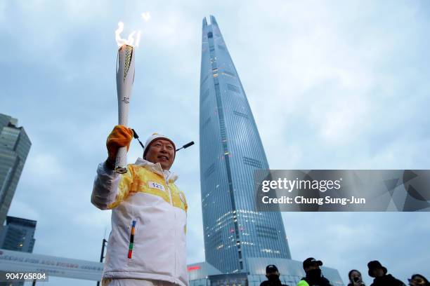 Shin Dong-bin, chairman of Lotte Group, holds the PyeongChang 2018 Winter Olympics torch in front of the Lotte World Tower during the PyeongChang...