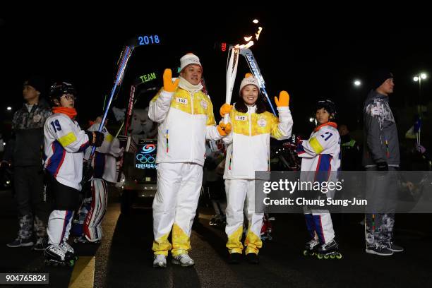 Torch bearers hold the PyeongChang 2018 Winter Olympics torch during the PyeongChang 2018 Winter Olympic Games torch relay on January 14, 2018 in...