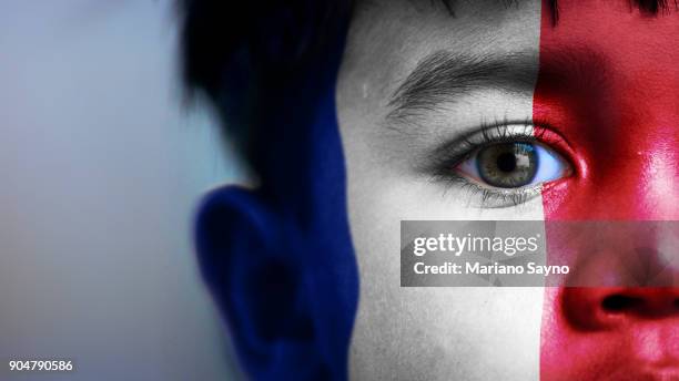 boy's face, looking at camera, cropped view with digitally placed france flag on his face. - body paint fotos stockfoto's en -beelden