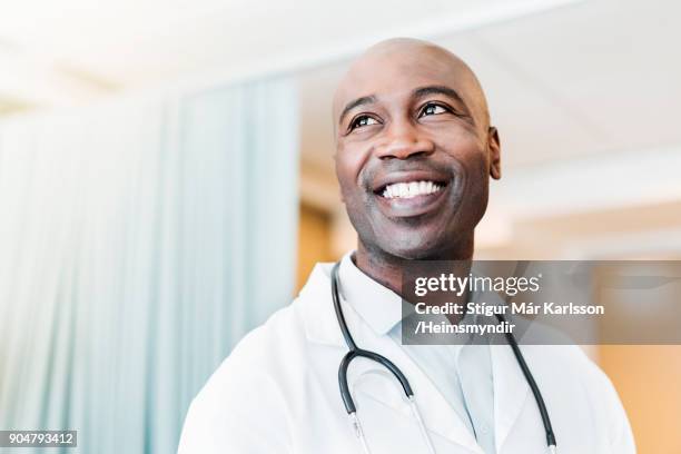 close-up of happy confident doctor looking away - male medical professional stock pictures, royalty-free photos & images