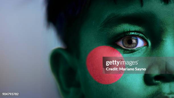 boy's face, looking at camera, cropped view with digitally placed bangladesh flag on his face. - bangladesh national flag stock-fotos und bilder