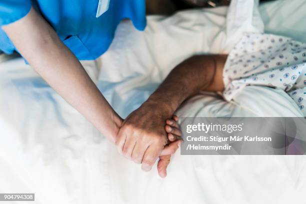 operatore sanitario che consola paziente in ospedale - holding hands close up foto e immagini stock