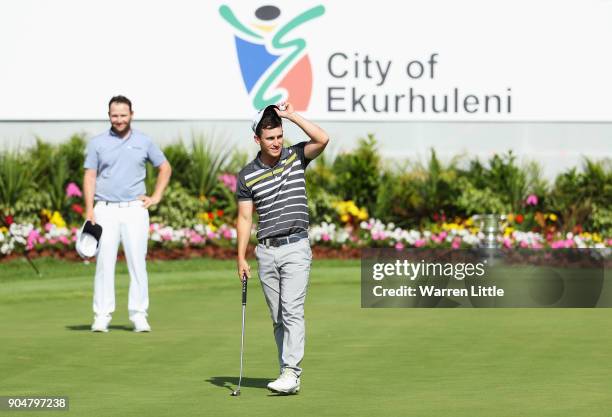 Chris Paisley of England celebrates victory on the 18th green watched by Branden Grace of South Africa during day four of the BMW South African Open...