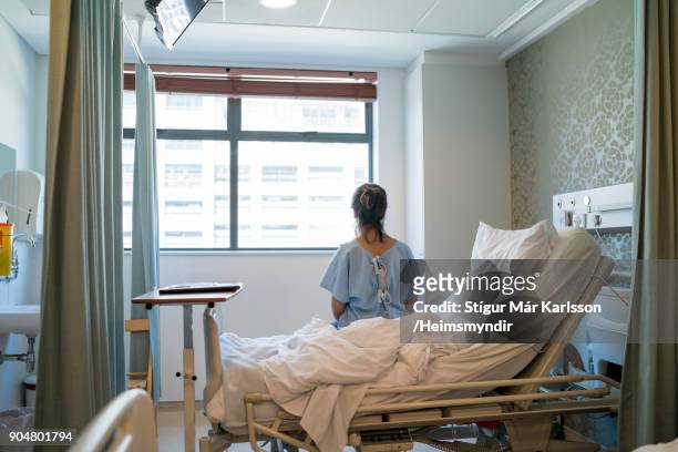 paziente seduta a letto nel reparto ospedaliero - woman from behind foto e immagini stock
