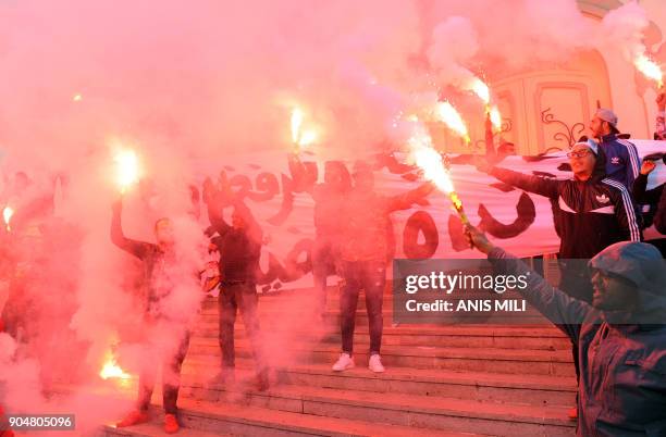 Tunisian protesters carry flares and shout slogans during celebrations in central Tunis on January 14 marking the seventh anniversary since the...