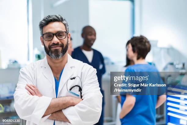 doctor with arms crossed against colleagues - doctor with arms crossed stock pictures, royalty-free photos & images