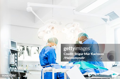 Surgeons operating below lighting equipment Surgeons operating below lighting equipment