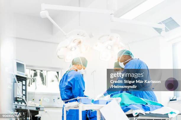 surgeons operating below lighting equipment - operation stock pictures, royalty-free photos & images