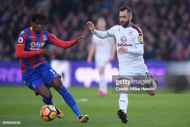 Wilfried Zaha of Crystal Palace is challenged by Steven Defour of Burnley during the Premier League match between Crystal Palace and Burnley at...