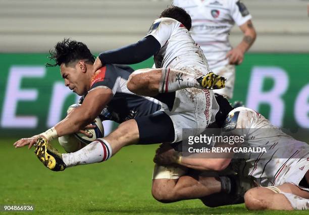 Castres' number eight Alex Tulou is tackled by Leicester's players during the European Champions Cup rugby union match between Castres Olympique and...