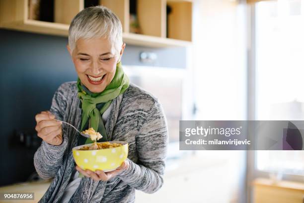 reife frau gesund frühstücken - women yogurt stock-fotos und bilder