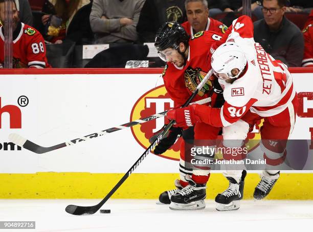 Nick Schmaltz of the Chicago Blackhawks and Henrik Zetterberg of the Detroit Red Wings battle for the puck along the boards at the United Center on...