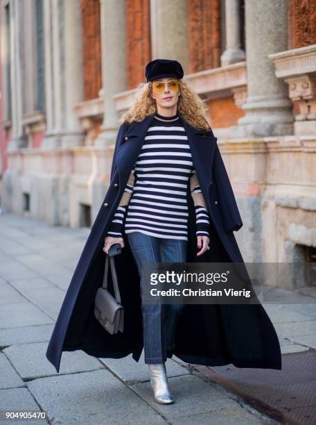 Elina Halimi wearing flat cap, striped top, coat, cropped denim jeans, silver boots is seen outside MSGM during Milan Men's Fashion Week Fall/Winter...