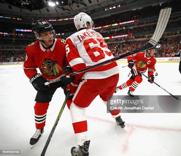 Patrick Kane of the Chicago Blackhawks flips a pass around Danny DeKeyser of the Detroit Red Wings at the United Center on January 14, 2018 in...