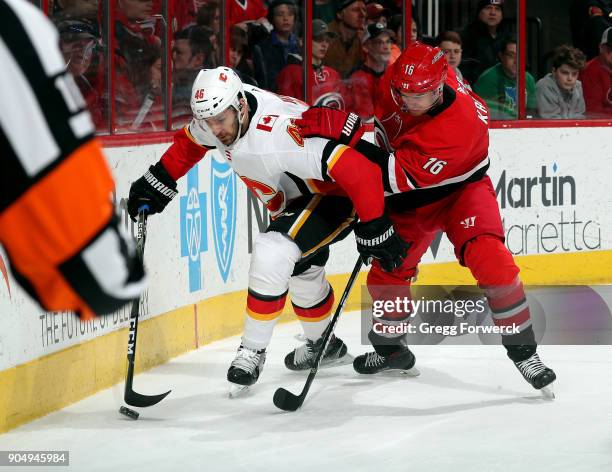 Marek Hrivik of the Calgary Flames hollds off Marcus Kruger of the Carolina Hurricanes as he advances the puck behind the goal during an NHL game on...