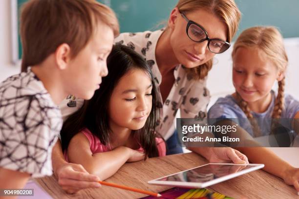 teacher explaining to pupils new things. debica, poland - asian child with new glasses ストックフォトと画像