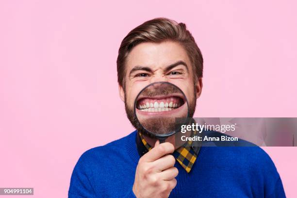 man holding magnifying glass against open mouth. debica, poland - snarling stock photos et images de collection