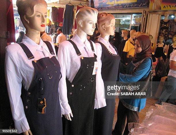 Woman looks at the a selection of female outfits in navy blue and white, which school and high school girls are allowed to wear when attending class,...