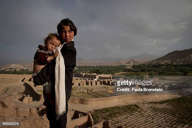 Sharifa holds her brother Mismillah, 13 months standing outside their cave dwelling September 6, 2009 in Bamiyan, Afghanistan. Many of the...