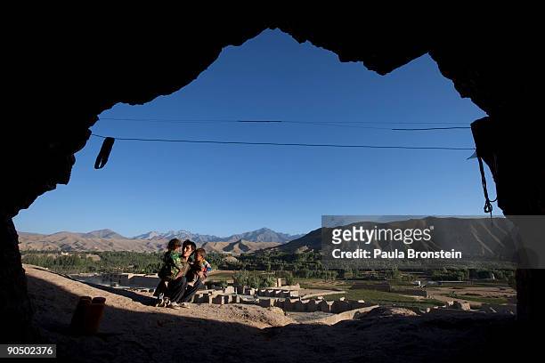 Father holds his children outside their cave dwelling September 7, 2009 in Bamiyan, Afghanistan. Many of the impoverished families living in the...