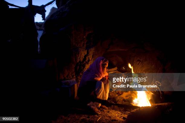 Sukinah cooks potatoes over an open fire in a makeshift kitchen, cave dwelling September 2, 2009 in Bamiyan, Afghanistan. Many of the impoverished...