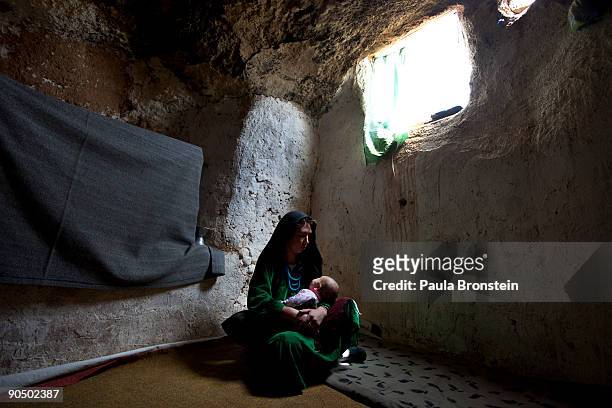 Mother holds her baby inside their cave dwelling September 2, 2009 in Bamiyan, Afghanistan. Many of the impoverished families living in the caves say...