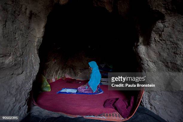 Anifa prays inside her cave dwelling where she lives with her family, September 7, 2009 in Bamiyan, Afghanistan. Many of the impoverished families...
