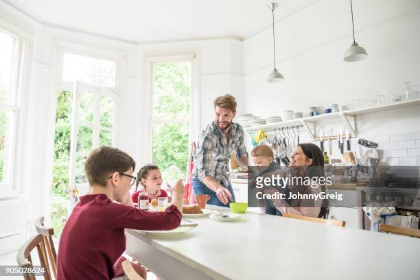 fröhliche familie in küche frühstücken, mutter halten baby und lächeln - 6 11 monate stock-fotos und bilder