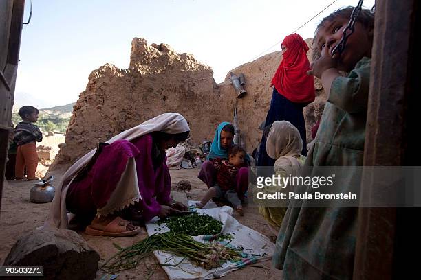 Women and children prepare dinner outside their cave September 5, 2009 in Bamiyan, Afghanistan. Many of the impoverished families living in the caves...