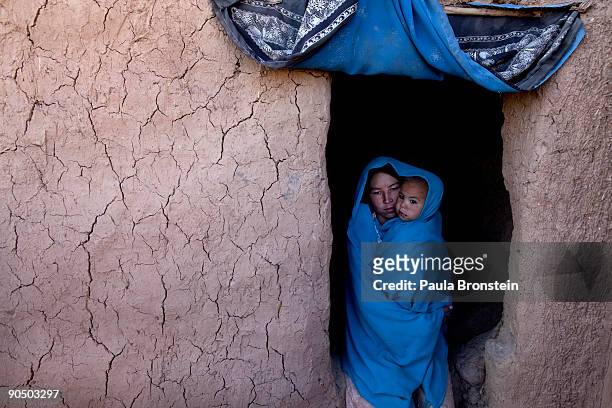 Sima holds her baby Farzana outside their cave dwelling September 2, 2009 in Bamiyan, Afghanistan. Many of the impoverished families living in the...