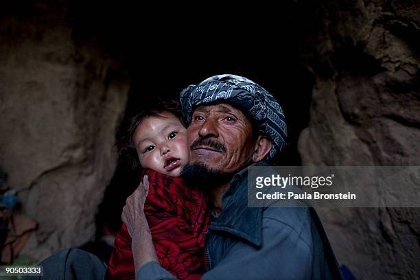 Reza, holds his daughter Hadisha, 16 months, inside their cave dwelling September 7, 2009 in Bamiyan, Afghanistan. Many of the impoverished families...