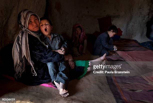 Rokia holds her son Reza as he yawns and his siblings Fauzia and Mohammed sit in their cave dwelling on September 7, 2009 in Bamiyan, Afghanistan....