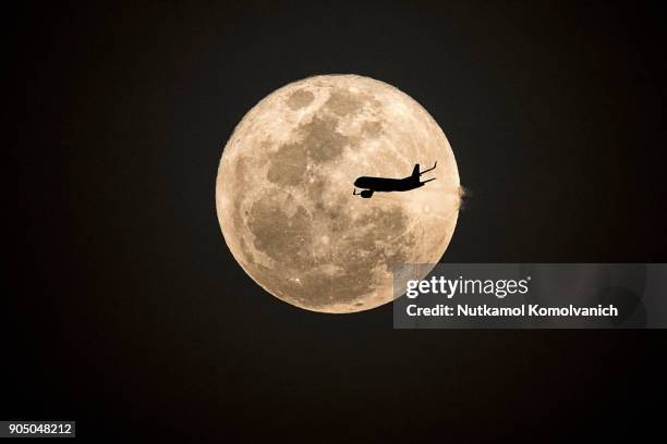aircraft fly pass supermoon at night - supermoon fotografías e imágenes de stock