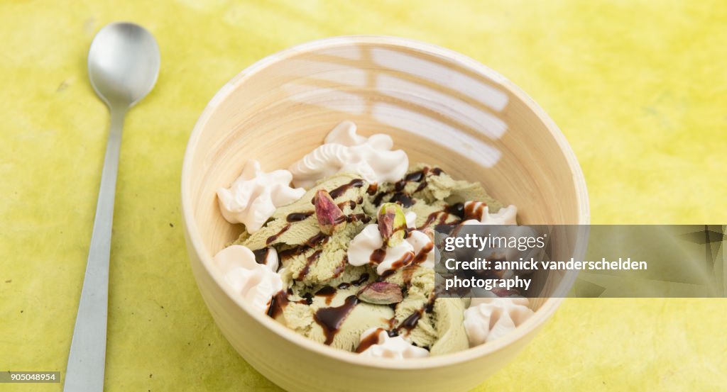 Pistachio scoop ice cream served in wooden bowl.