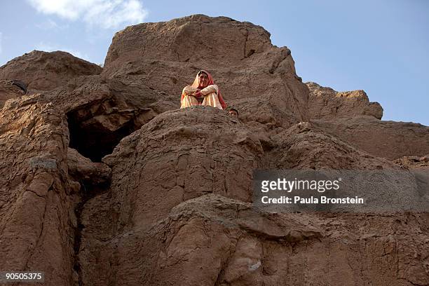 Woman sits on a cliff outside her cave dwelling September 2, 2009 in Bamiyan, Afghanistan. Many of the impoverished families living in the caves say...