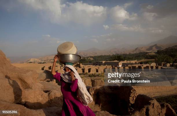 Woman carries dishes back to her dwelling September 2, 2009 in Bamiyan, Afghanistan. Many of the impoverished families living in the caves say they...