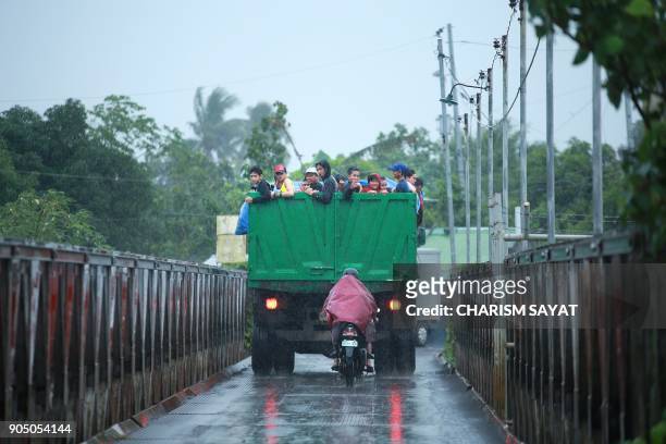 Residents ride on the back of a truck as they are evacuated to a temporary shelter due to Mayon volcano's eruption in Camalig town, Albay province,...