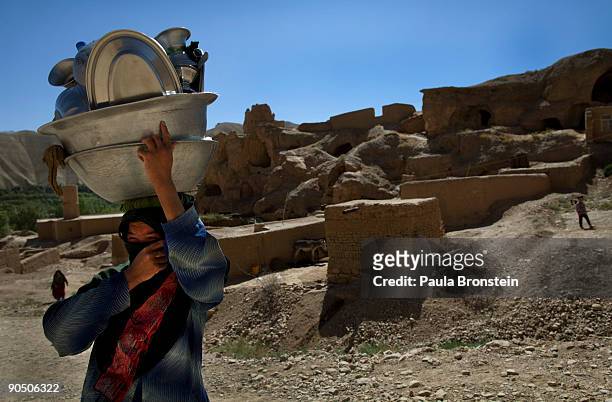 Woman carries dishes on her head as she walks back to her cave September 2, 2009 in Bamiyan, Afghanistan. Many of the impoverished families living in...