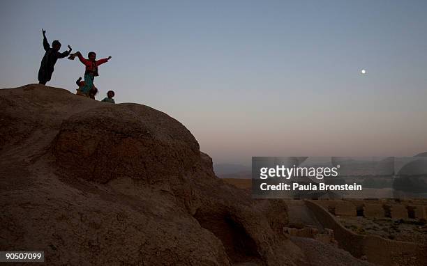 Children dance and play on the cliffs as a full moon rises September 6, 2009 in Bamiyan, Afghanistan. Many of the impoverished families living in the...